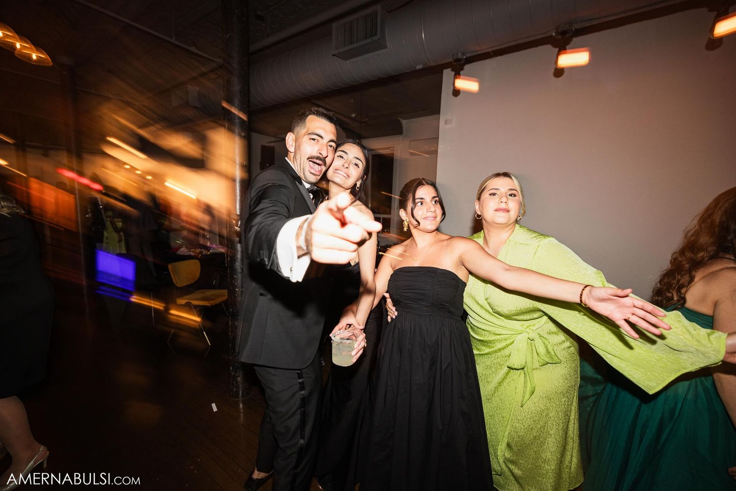 Party guests strike dramatic poses during a celebration under ambient lighting.