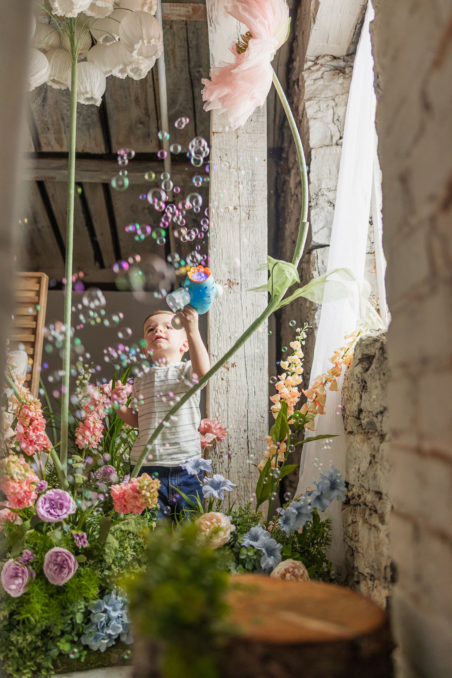 A magical scene with soap bubbles floating among pink and blue flowers in a rustic setting.