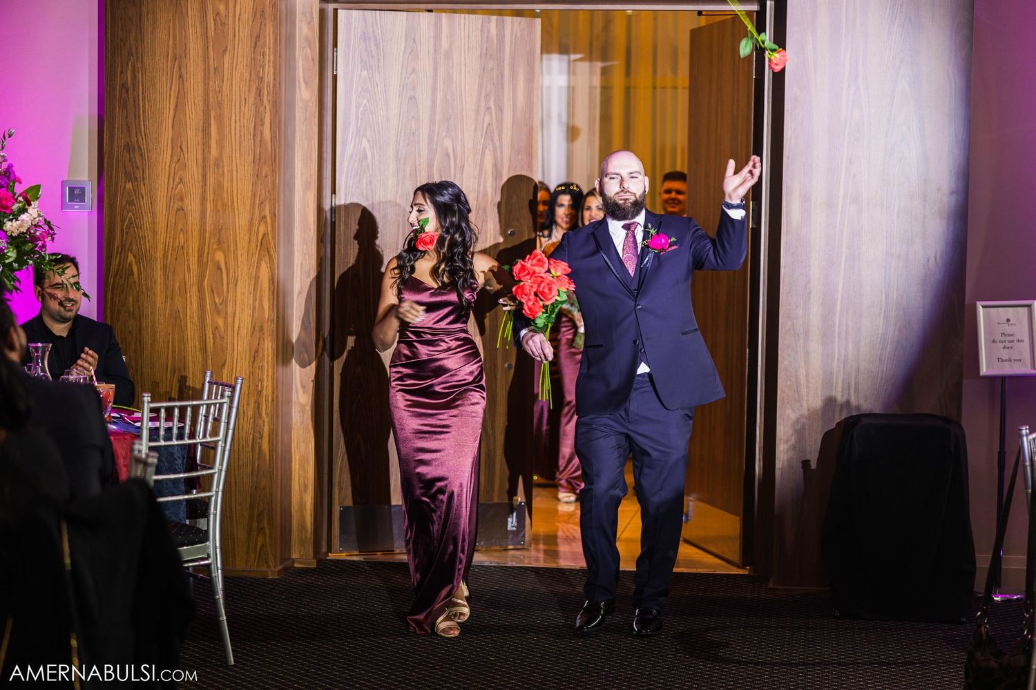 Celebratory entrance into reception hall with pink lighting and floral arrangements.