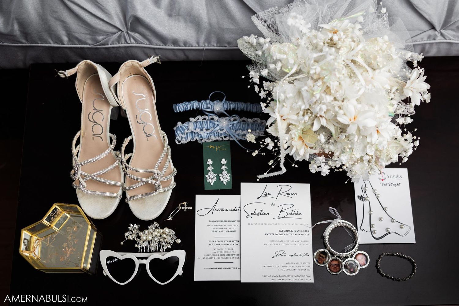 Wedding details flatlay with shoes, invitation, rings, and white floral bouquet.