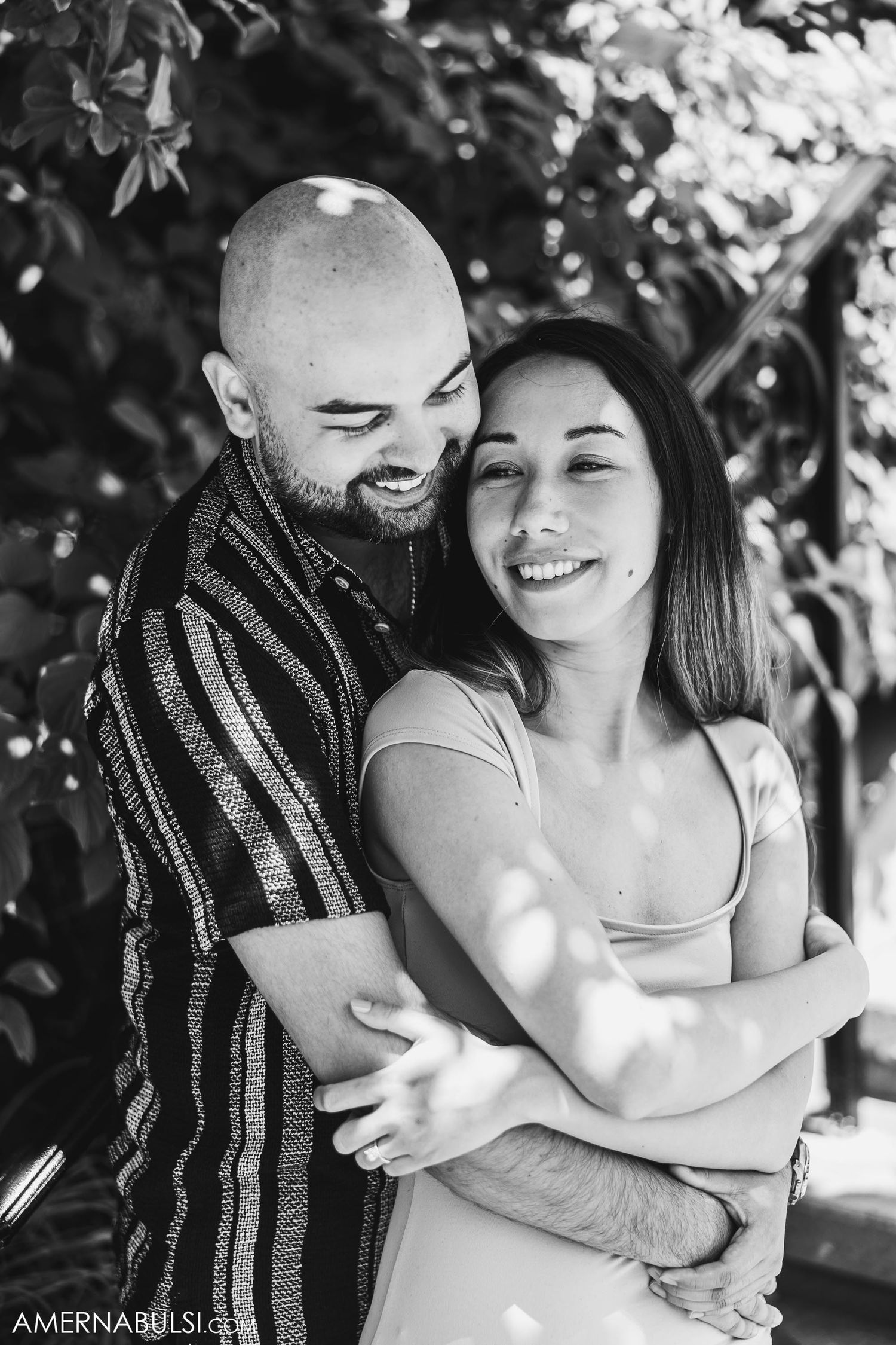 Black and white portrait of a joyful couple laughing while embracing outdoors.