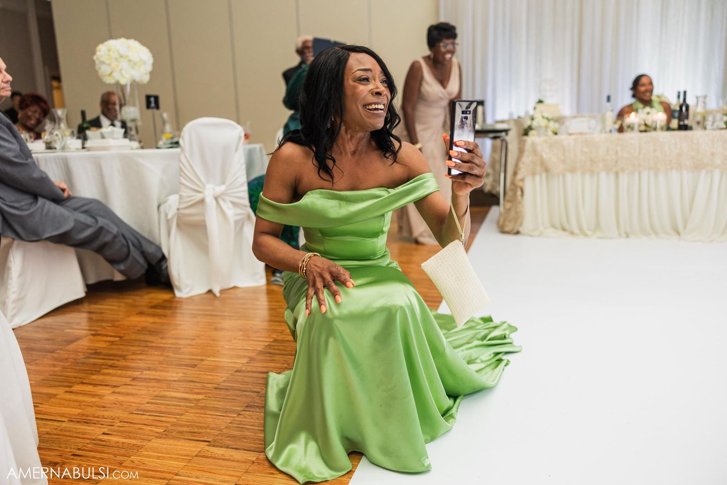 Wedding guest in a vibrant green dress dances enthusiastically at the reception.