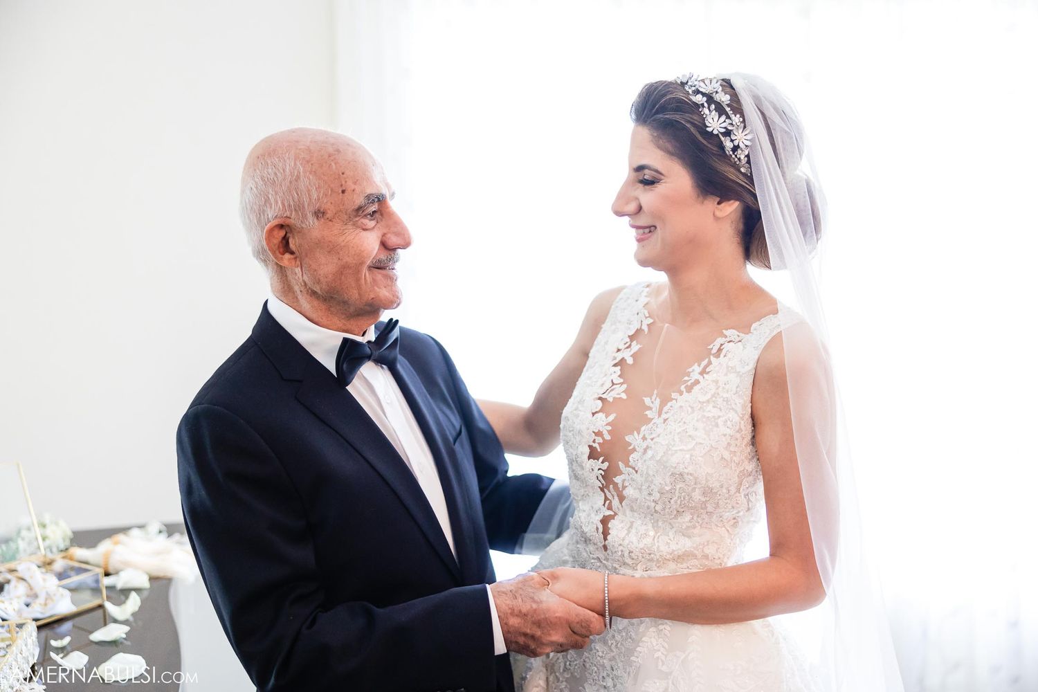 Touching pre-wedding moment with senior gentleman and bride in elegant lace gown.