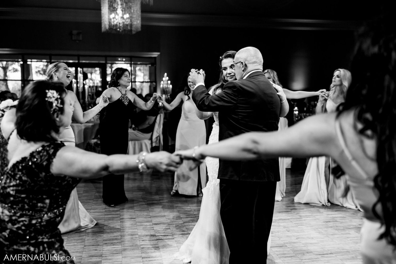 A lively black and white photo of wedding guests dancing and celebrating on the dance floor.
