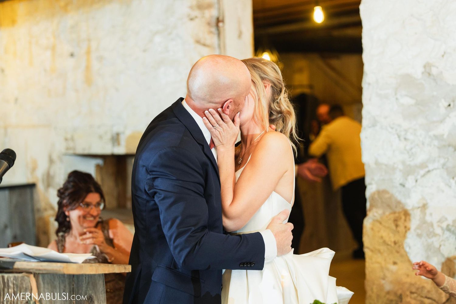 Romantic moment captured during wedding reception in rustic indoor venue.