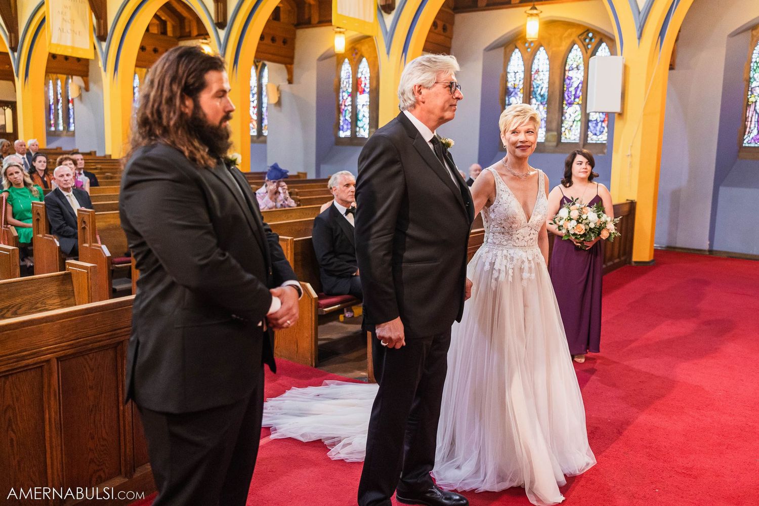 Wedding ceremony participants standing at altar in ornate church interior.