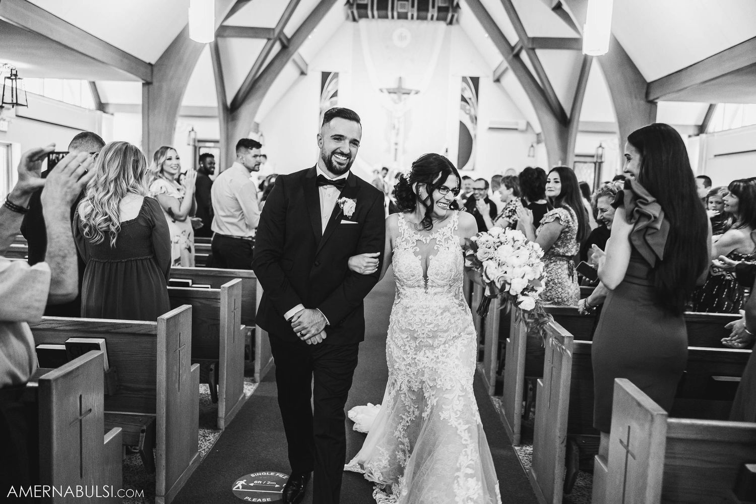 Black and white photo of newlyweds walking down church aisle after ceremony.