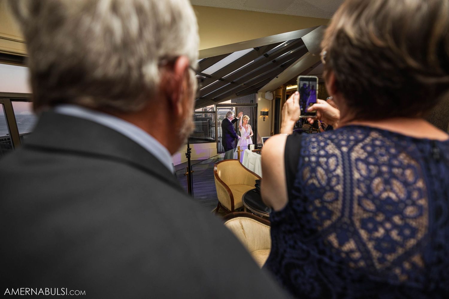 Wedding guests take photos during a celebration in an indoor venue.