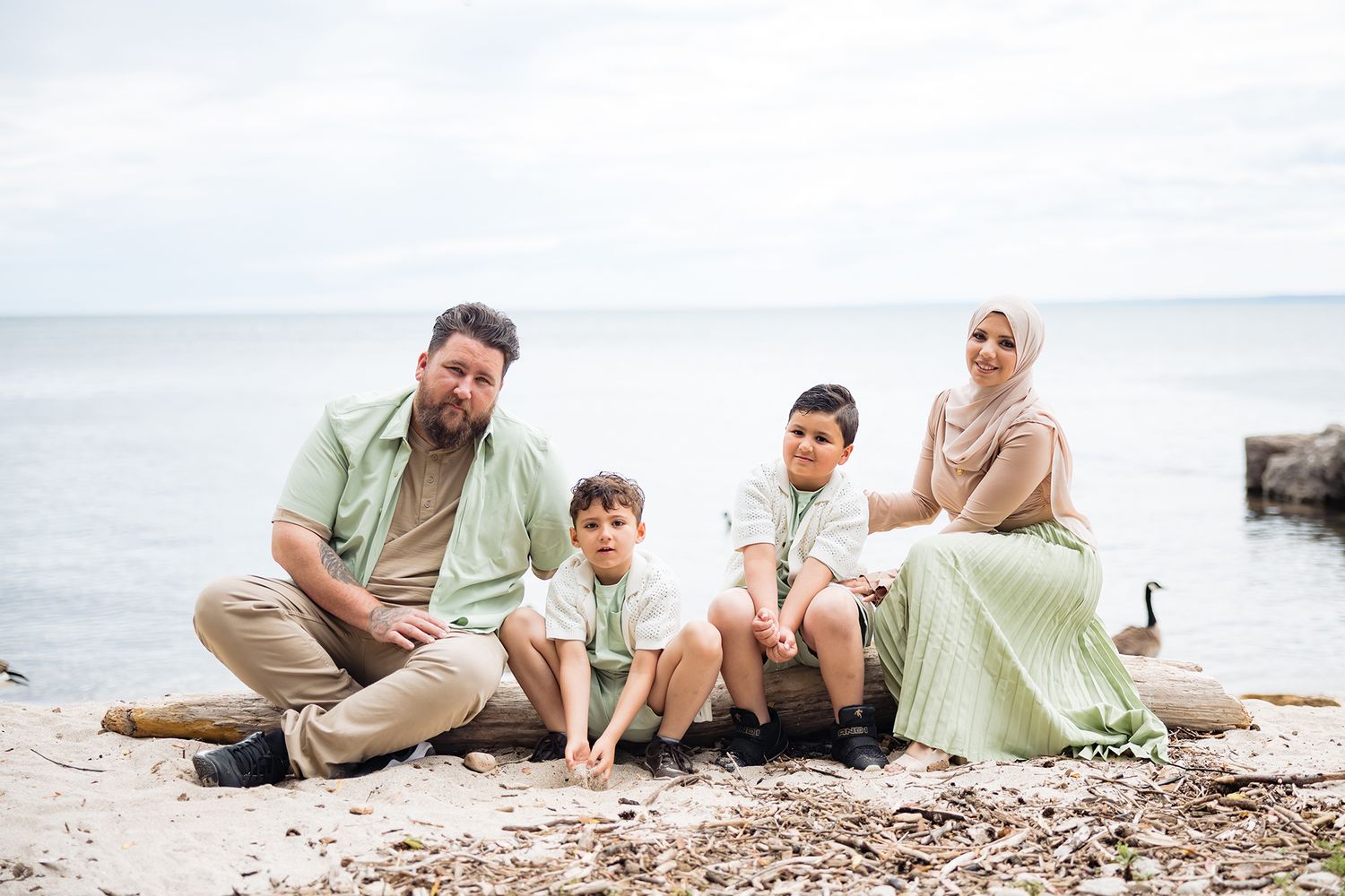 Family sitting together on a beach during sunset photo session.