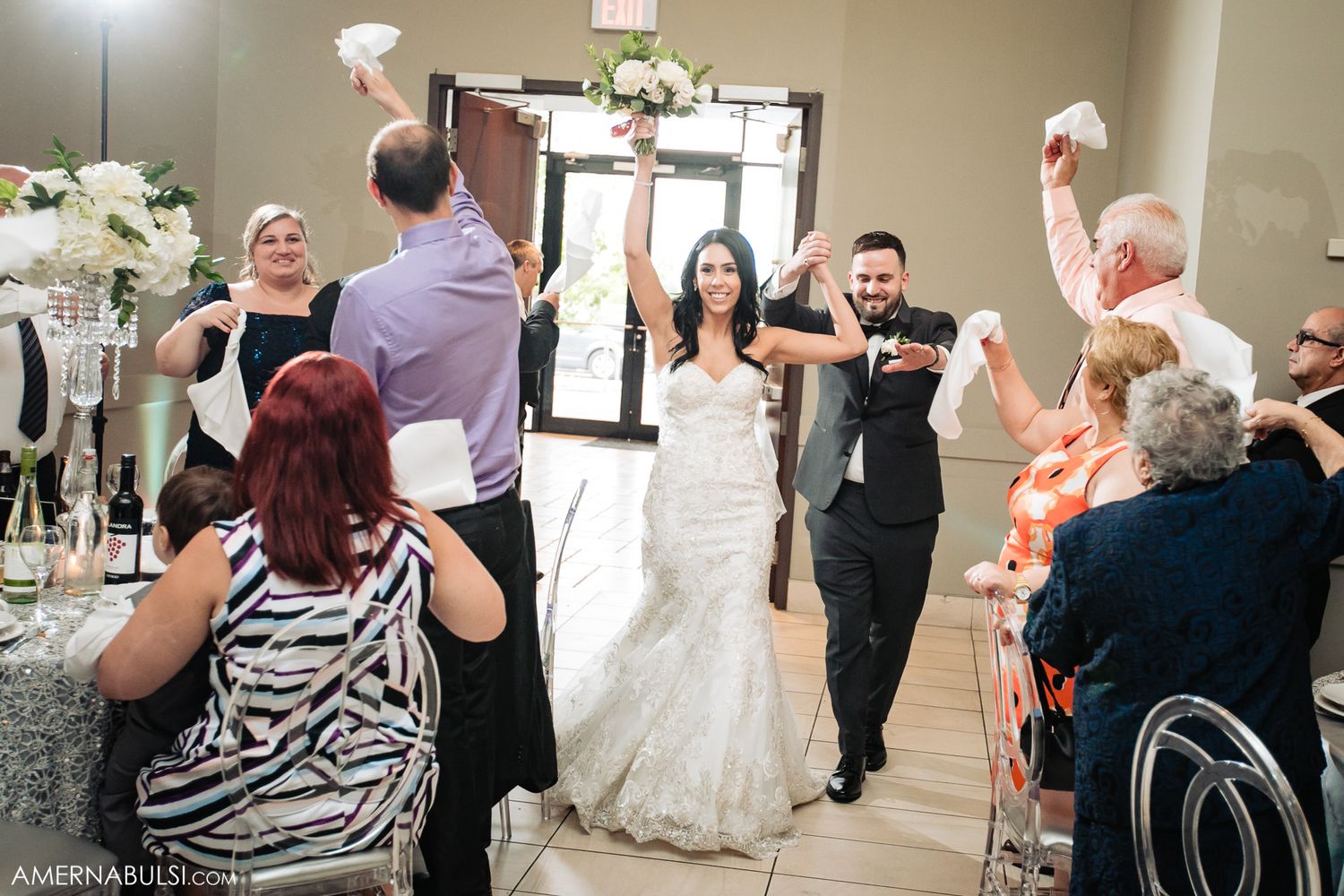 Wedding party entrance at reception with guests throwing paper airplanes in celebration.