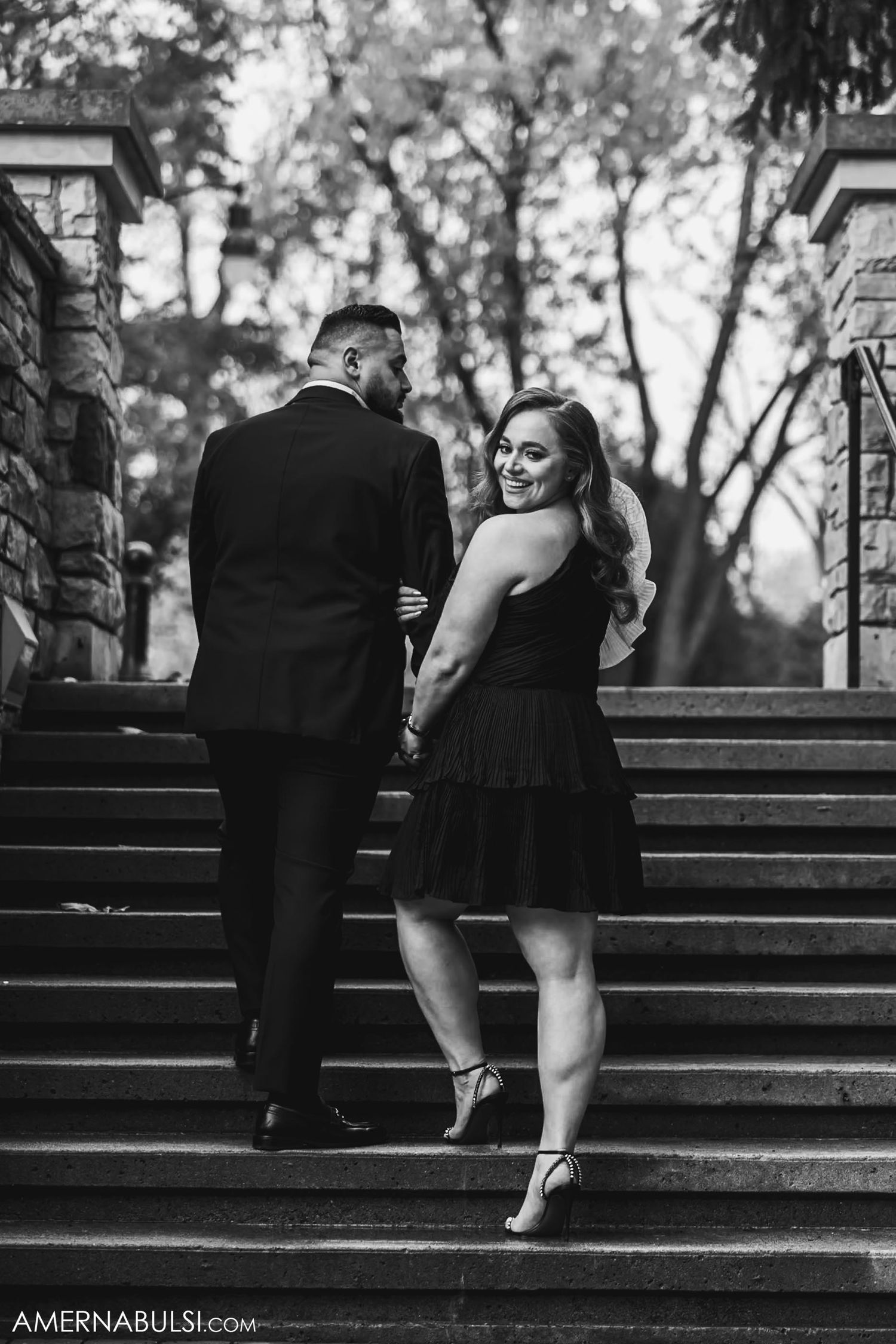A couple ascends stone steps during their engagement photoshoot.