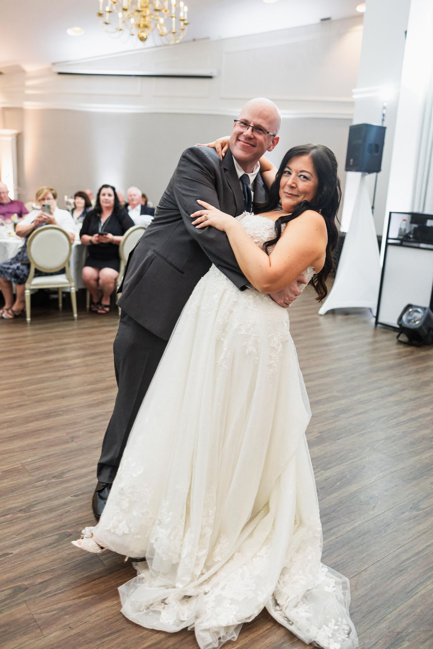 A joyful dance moment captured at a wedding reception on a wooden dance floor.