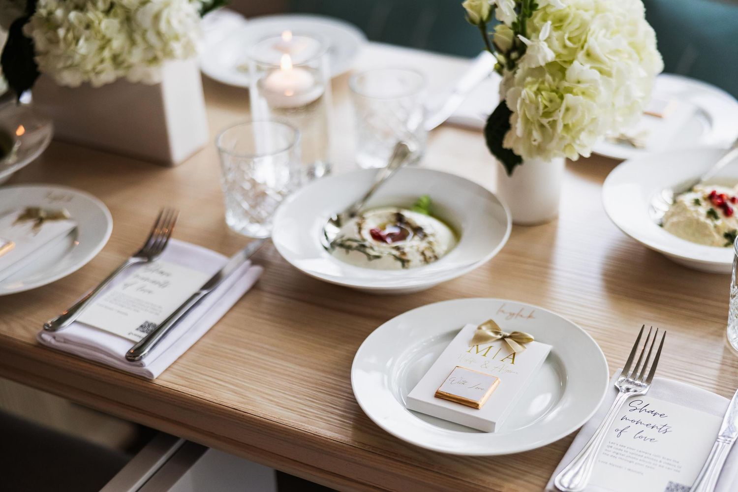 Minimalist wedding table setting with white flowers and plated meals.