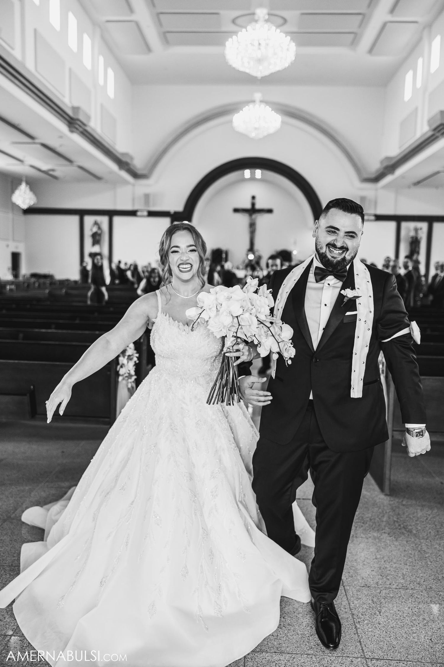 Newlyweds celebrate with exuberant joy while walking down church aisle after ceremony.