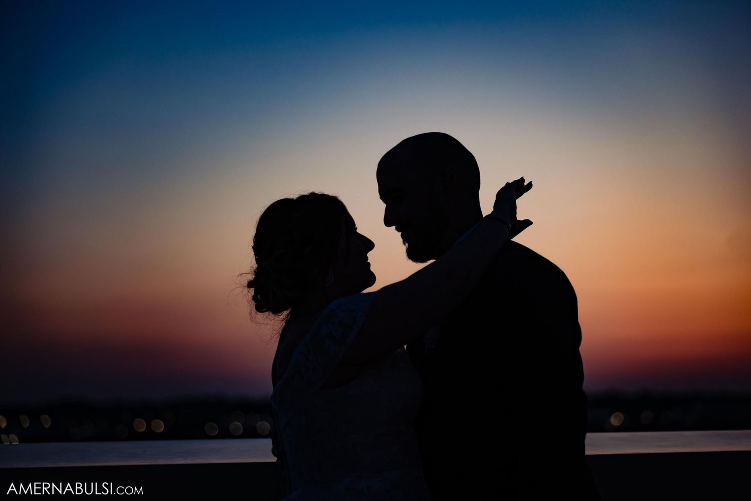 Silhouette of couple against vibrant sunset sky over water.