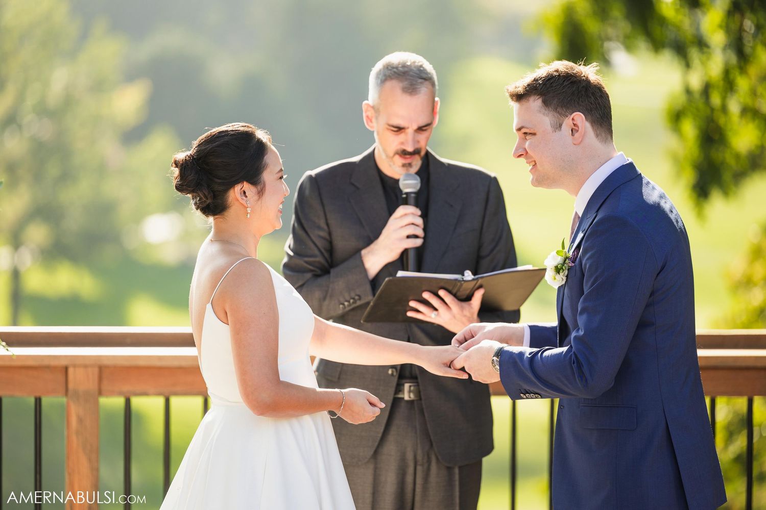 Bride and groom exchange vows during outdoor wedding ceremony with officiant.
