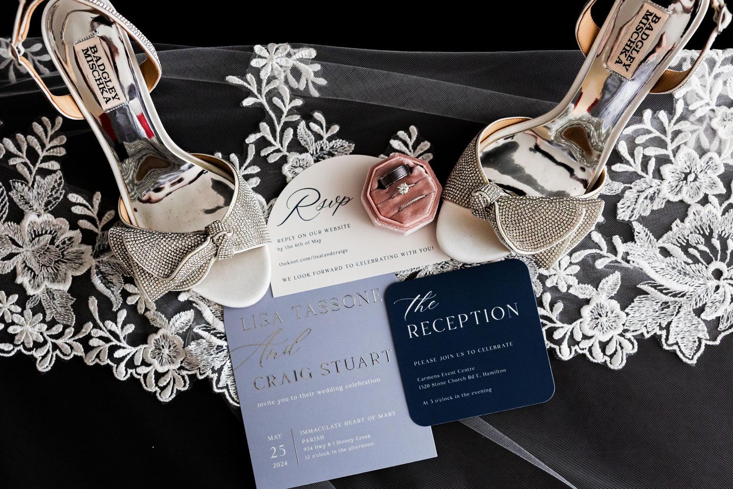 Wedding accessories including silver heels, lace veil, and navy blue invitation cards laid out together.