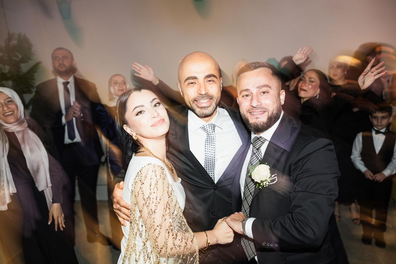 Three wedding guests share a joyful moment on the dance floor during the celebration.