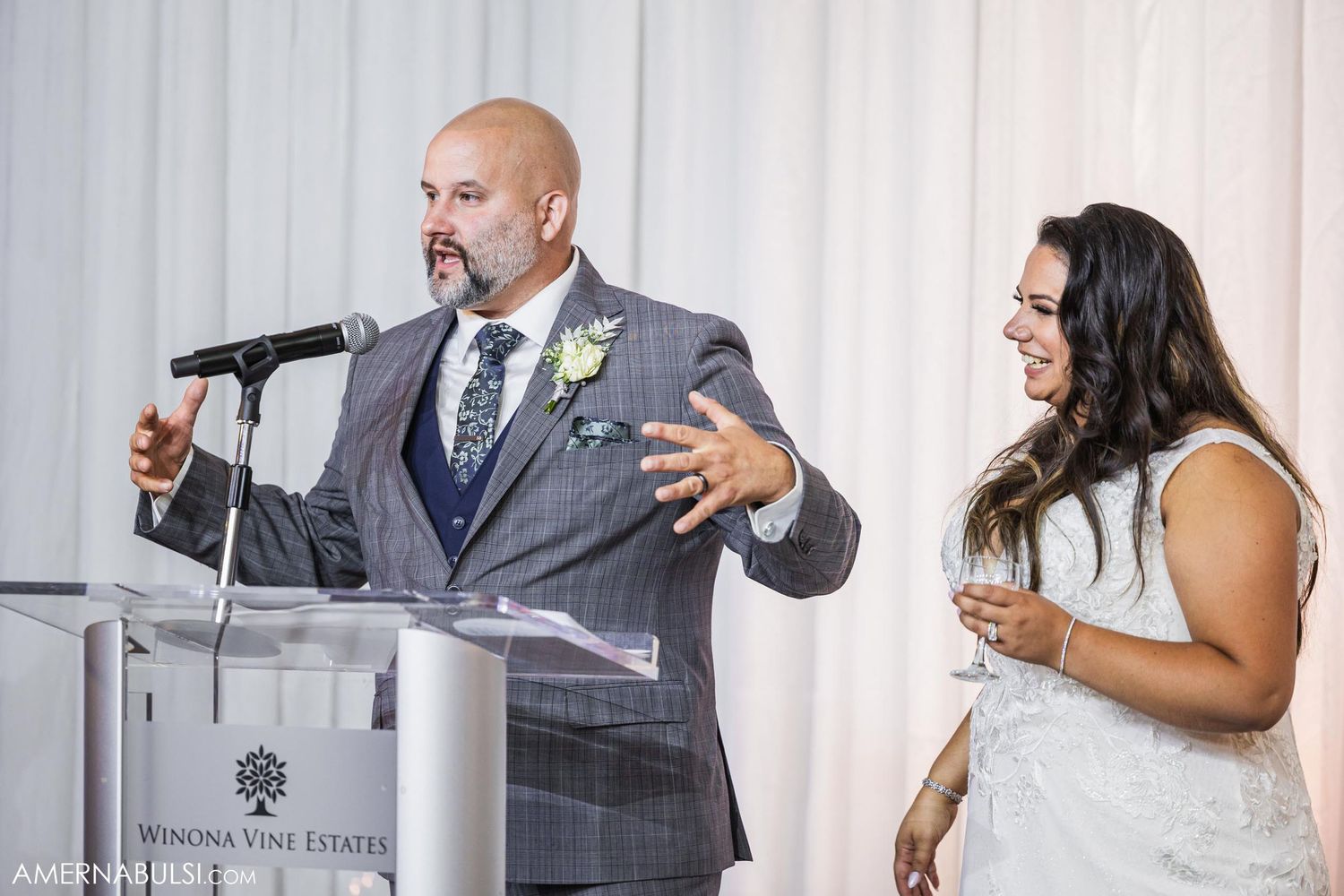 Couple speaking at a podium during their wedding reception.