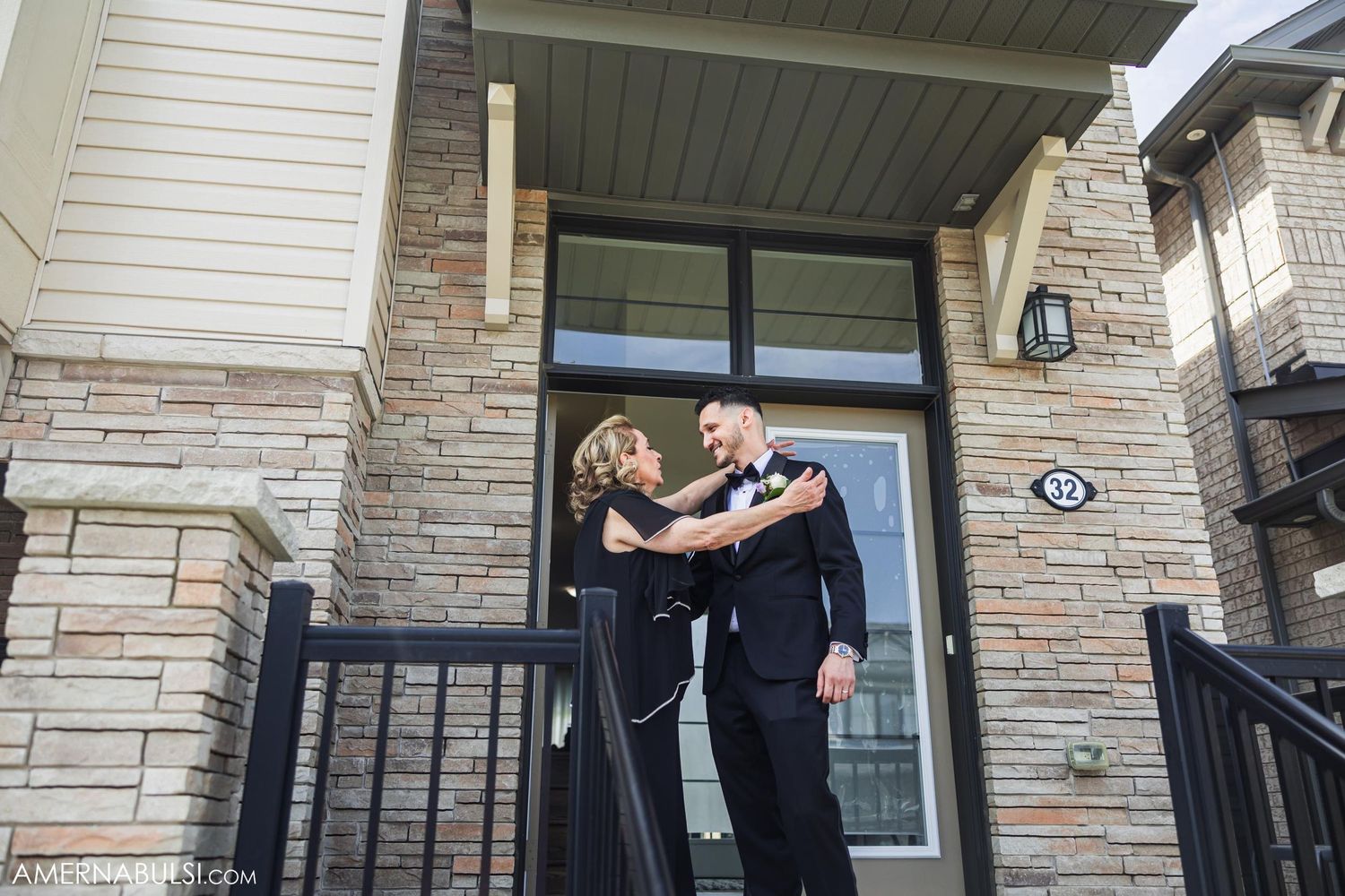 Couple embracing on front porch of stone facade house.