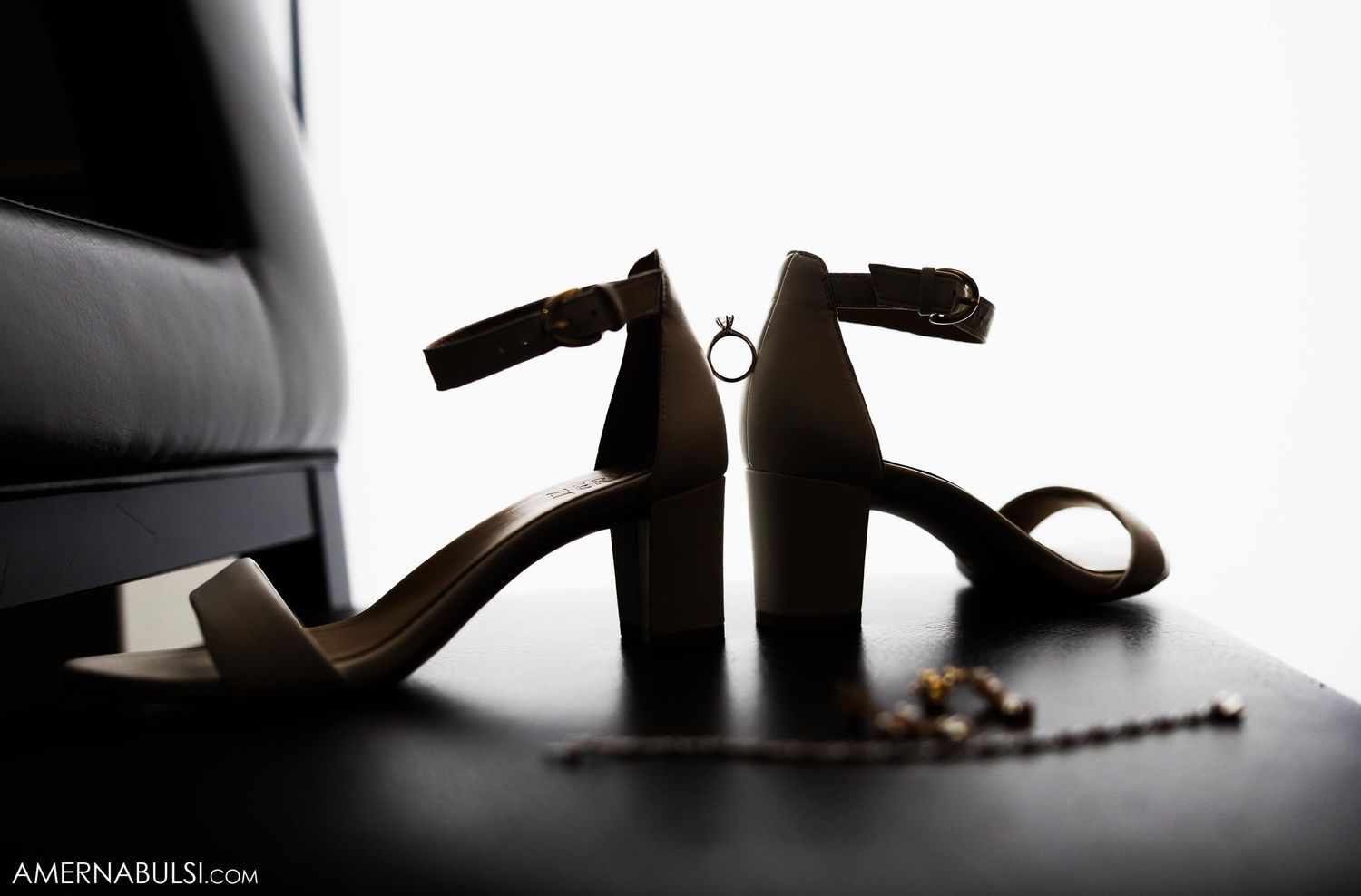Elegant wedding heels silhouetted against white background in artistic detail shot.