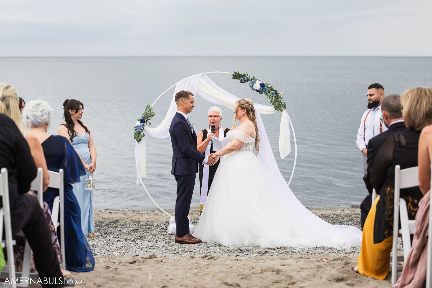 Wedding guests gathered on a scenic beach shoreline for an outdoor ceremony celebration.