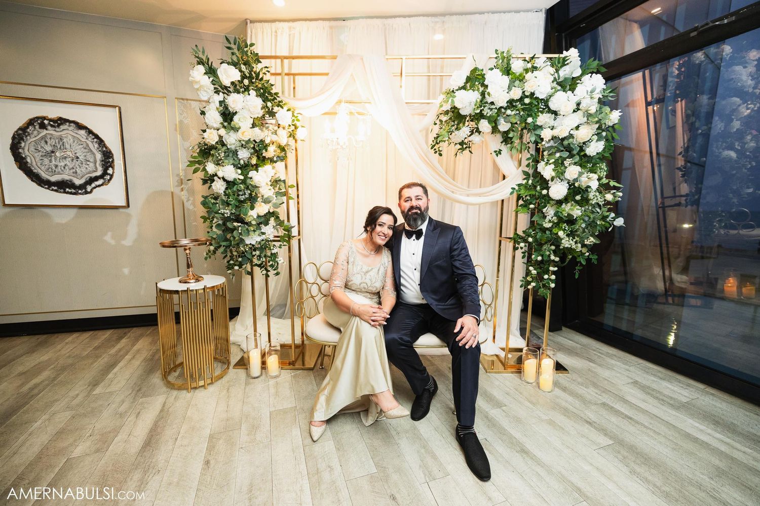 Wedding scene with floral arch decorations and wooden accents in modern indoor setting.
