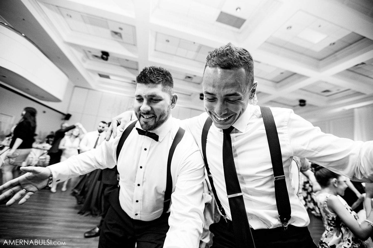 Wedding guests dance and celebrate together on an elegant ballroom dance floor at a reception.