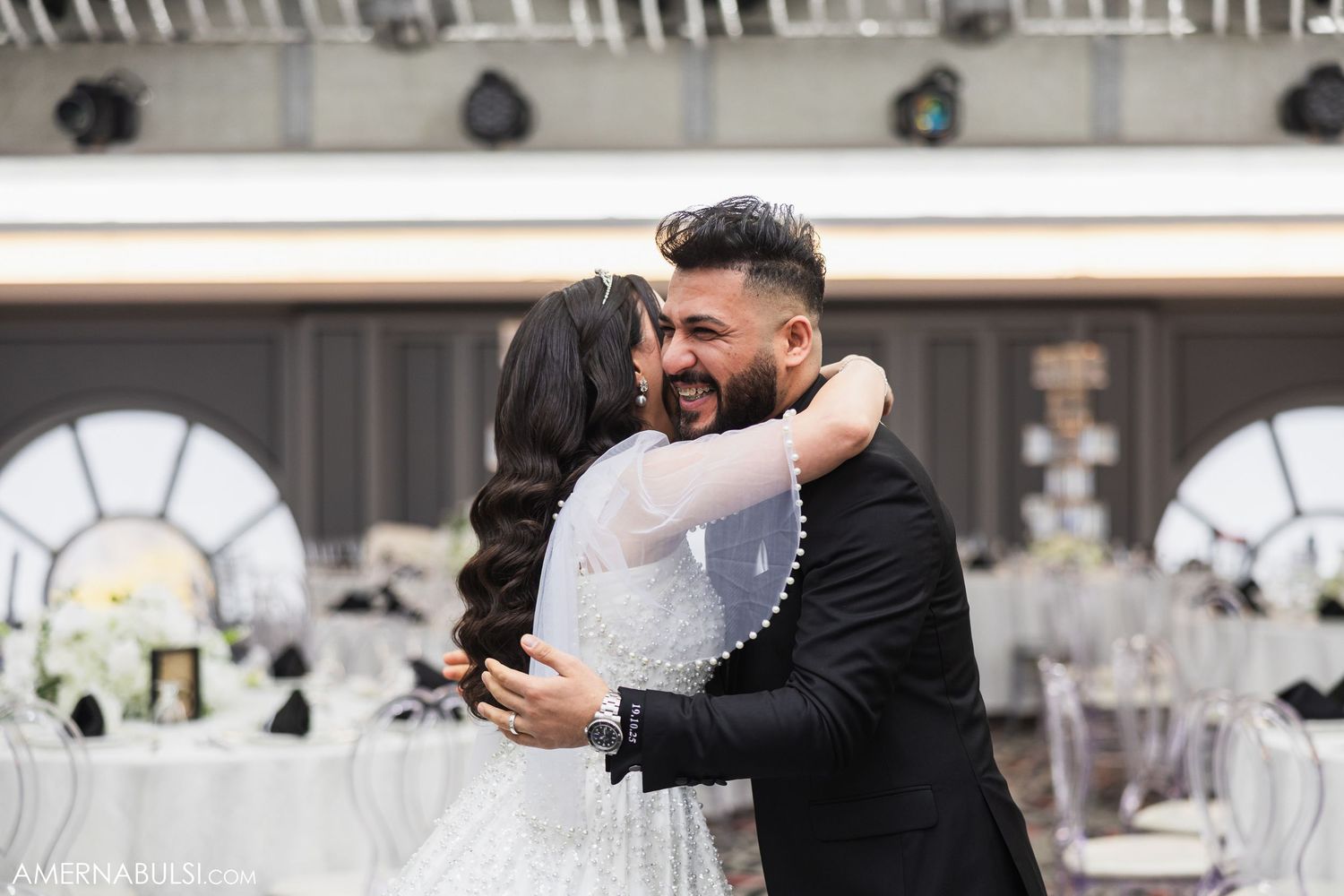 Couple embraces during their first look wedding moment in a beautifully decorated reception hall.