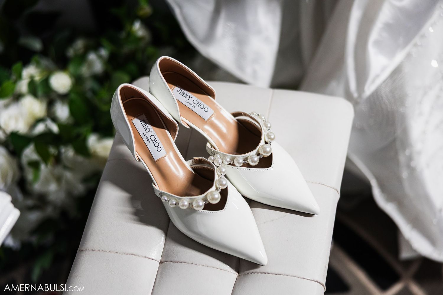 White bridal shoes arranged artistically with natural lighting and floral elements.