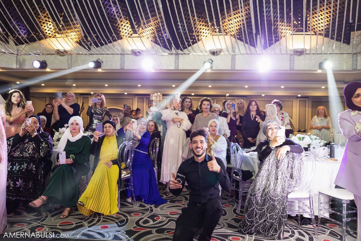 Wedding reception venue decorated with elegant lighting and filled with celebrating guests on the dance floor.