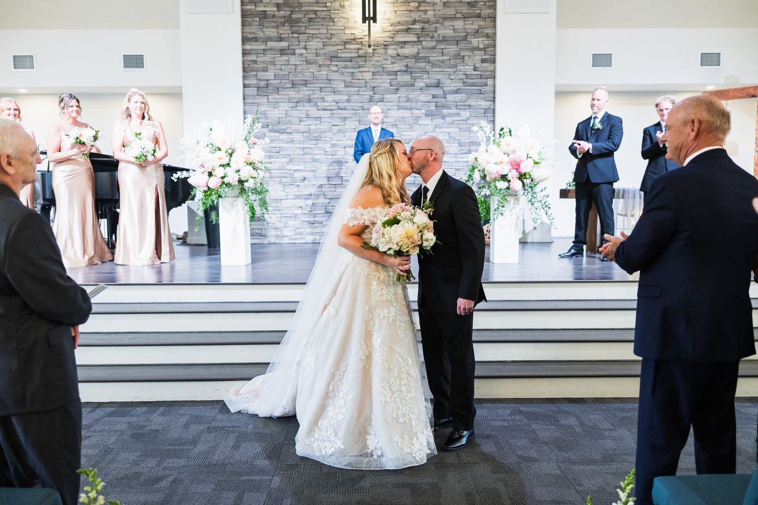 Modern wedding ceremony space with stone accent wall and guests seated in rows.