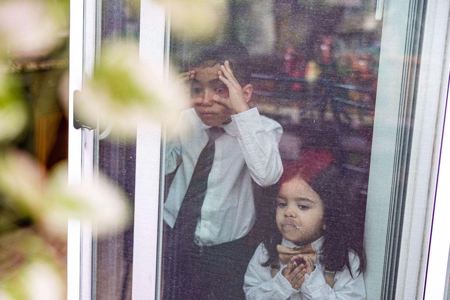 A playful moment captured through a window reflection with formal attire.