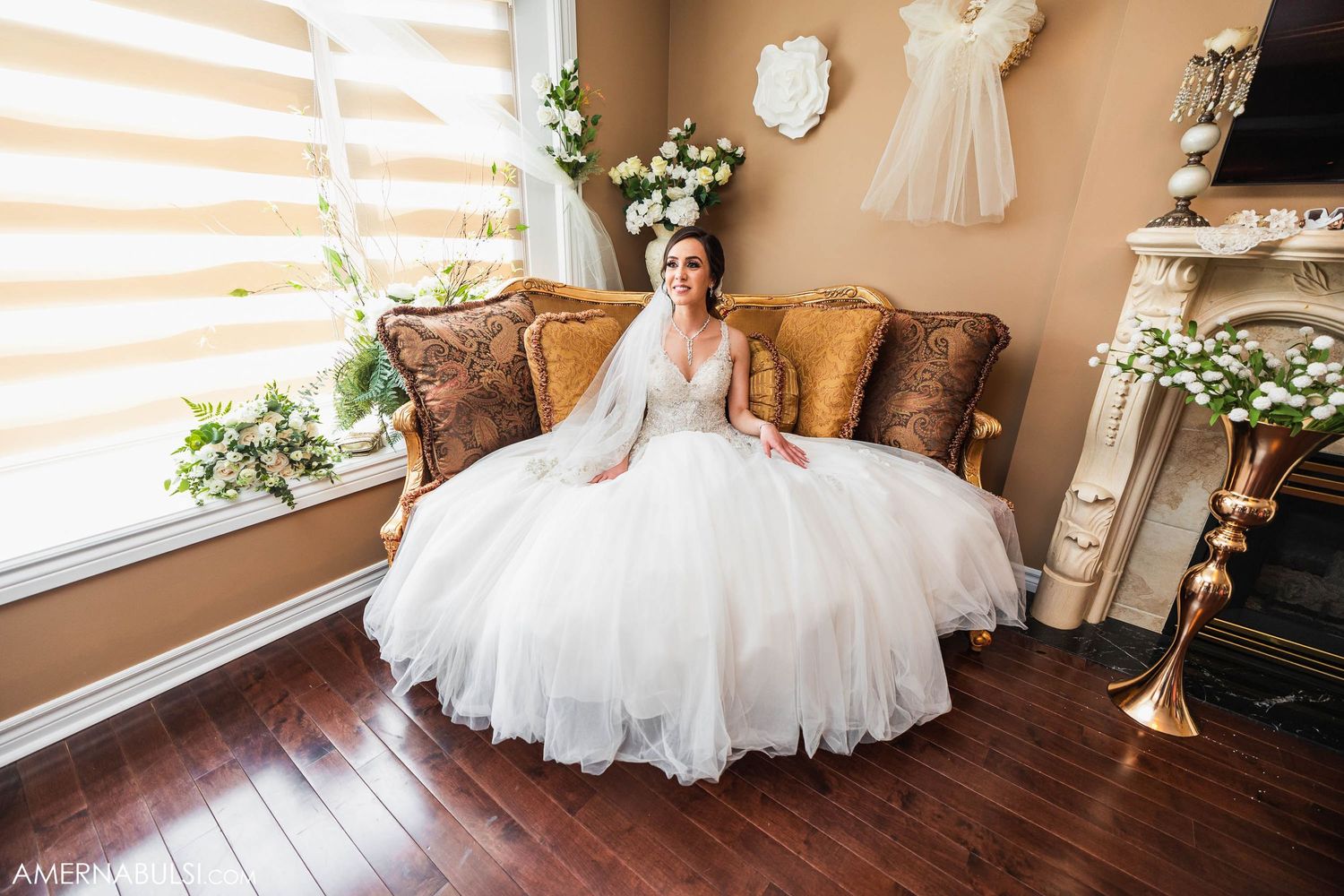 Elegant wedding preparation room with white gown displayed against warm-toned walls and decor.