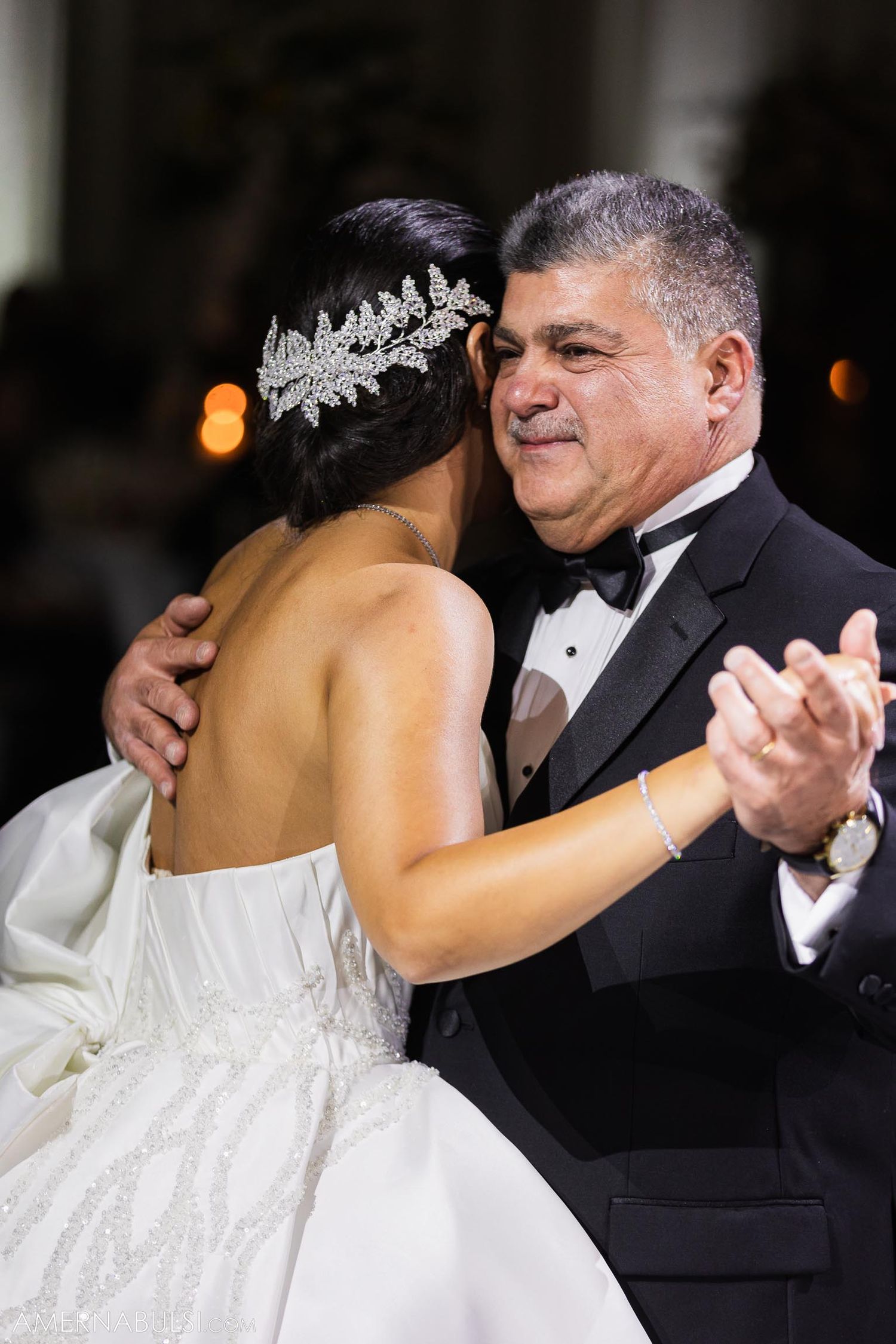 Elegant ballroom dance moment during wedding reception with sparkly hair accessory detail.