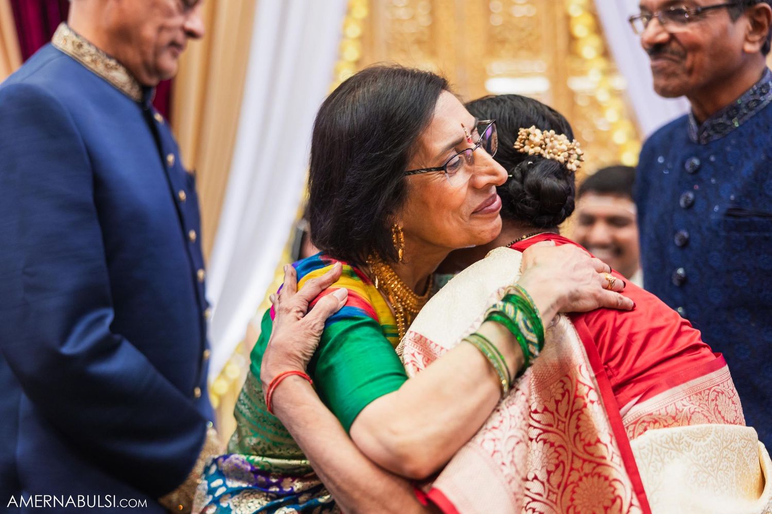 Emotional embrace shared during Indian wedding celebration with colorful traditional attire.