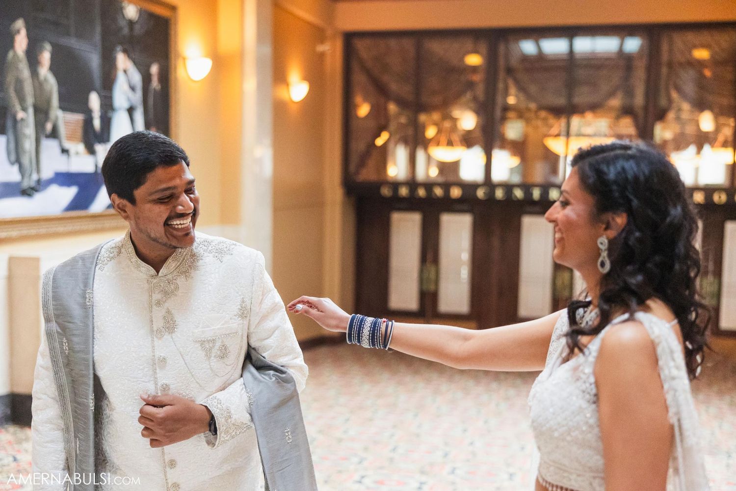 A candid wedding moment captured in an ornate indoor venue with warm lighting.