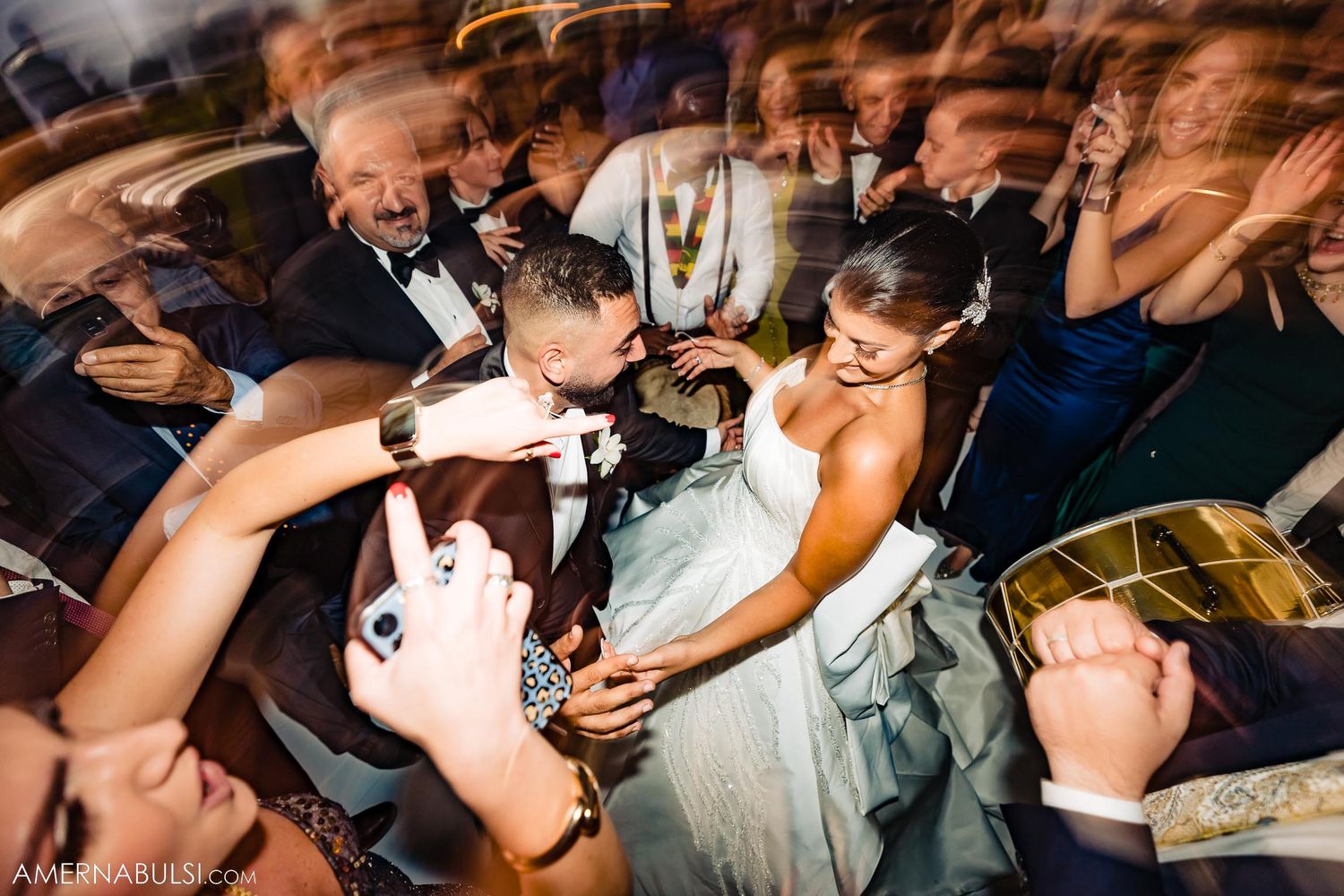 Dynamic wedding party celebration captured with motion blur in low light conditions.