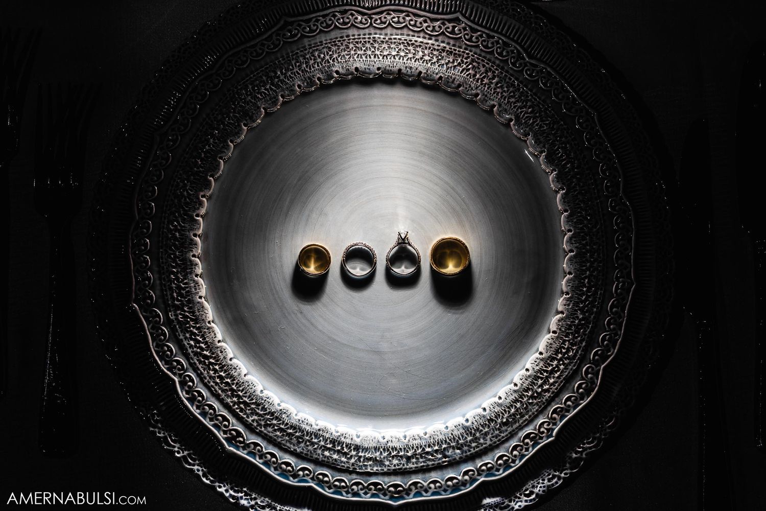Artistic macro shot of four wedding rings lined up in metallic circular setting.