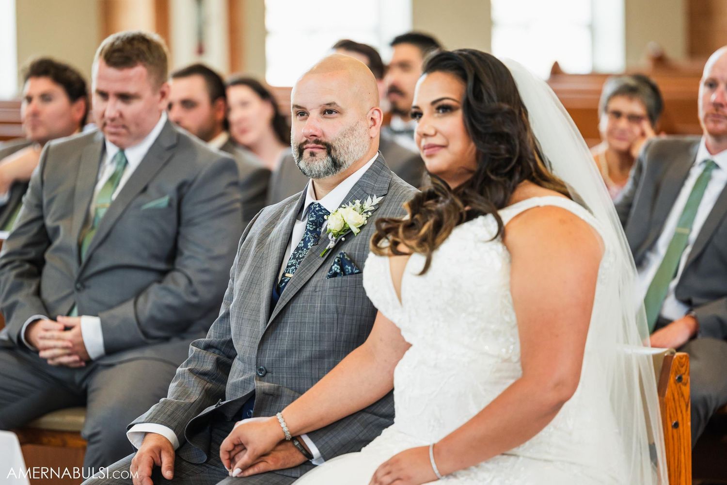A couple sits together during their wedding ceremony in a church sanctuary.