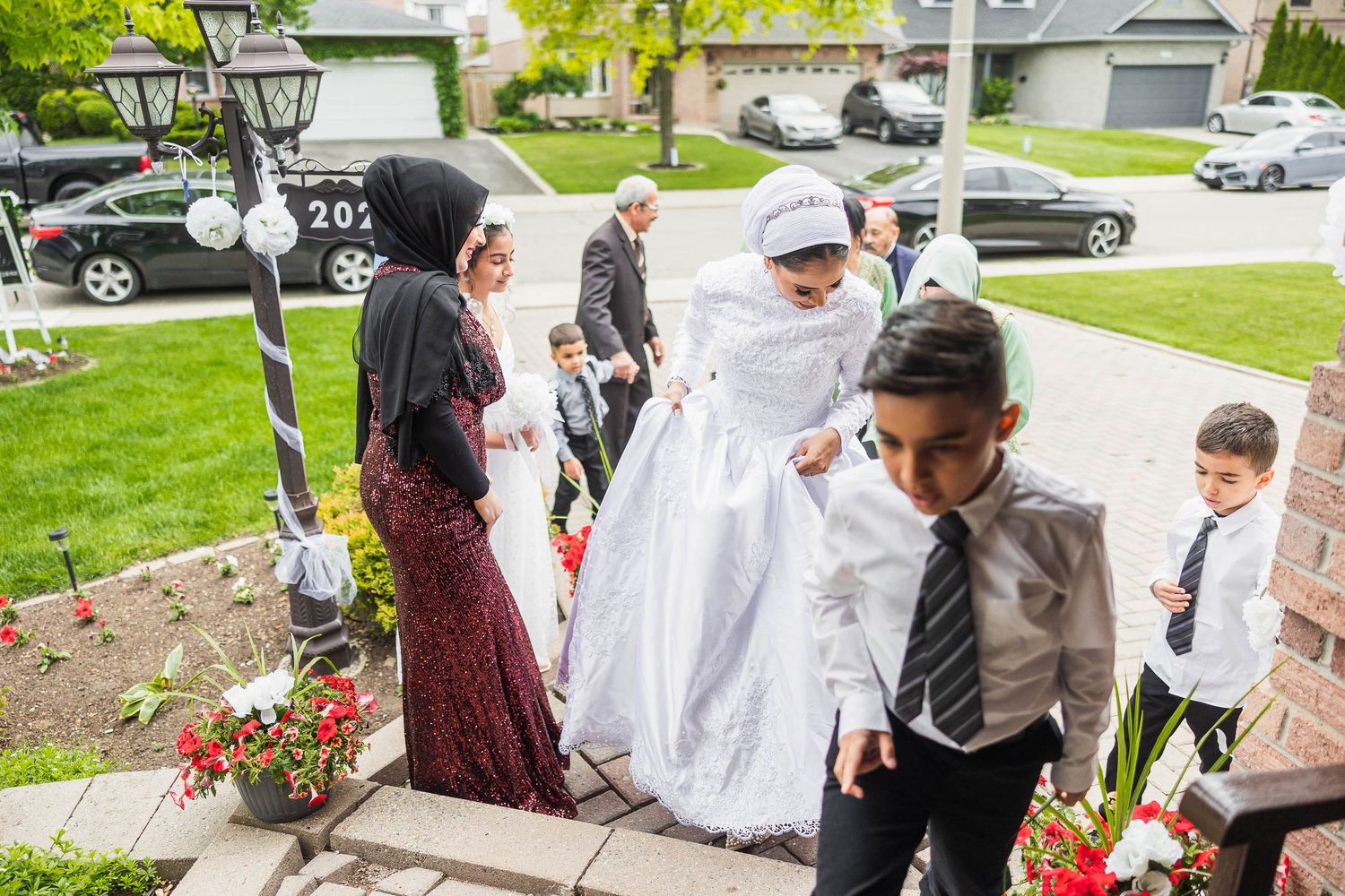 A wedding party gathering on outdoor steps with decorative flowers and umbrellas.