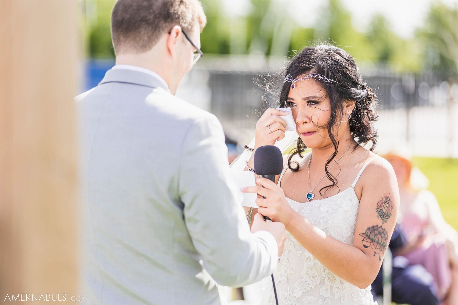 Emotional moment during outdoor wedding ceremony with microphone.