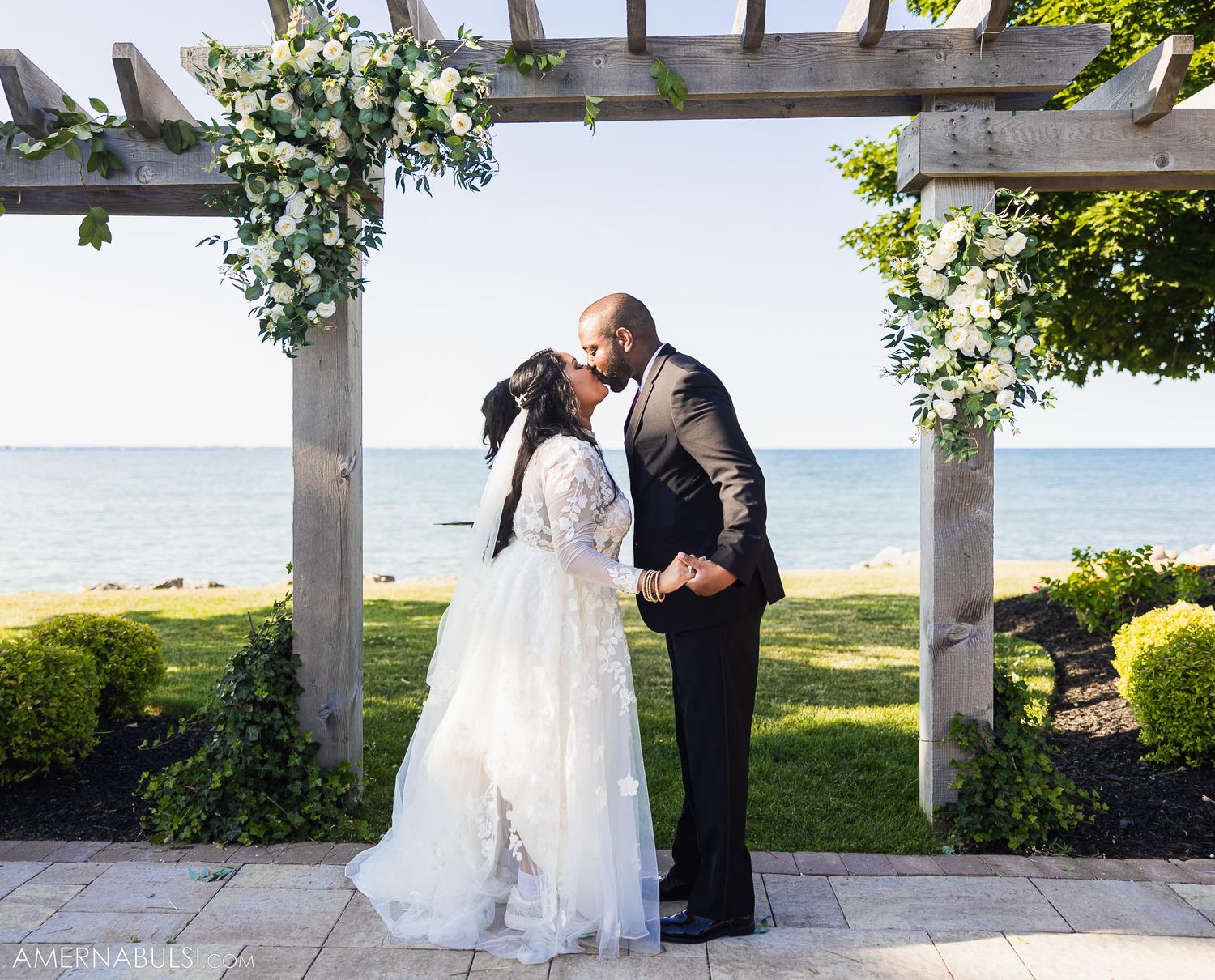 Romantic moment under white pergola decorated with flowers overlooking ocean view.