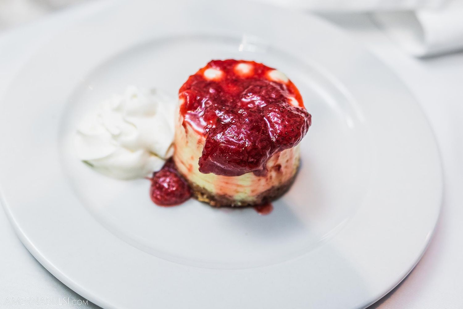 Dessert plate featuring a scone topped with red berry compote and whipped cream.