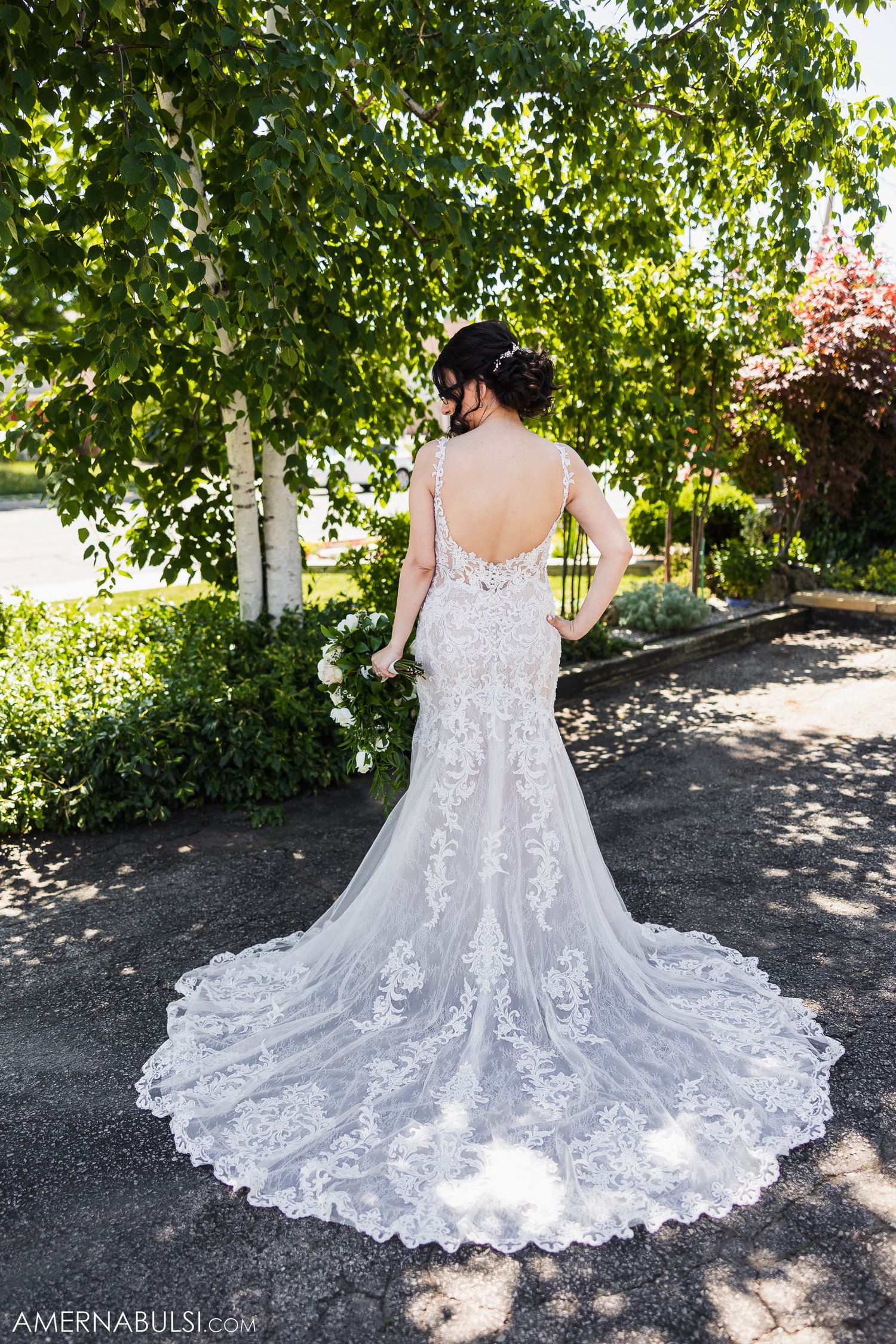Full length back view of lace wedding dress with dramatic cathedral train outdoors.