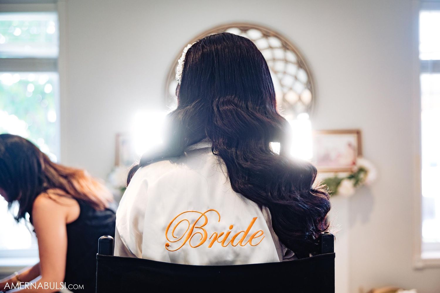 A white satin robe with 'Bride' embroidered in gold text seen from behind.
