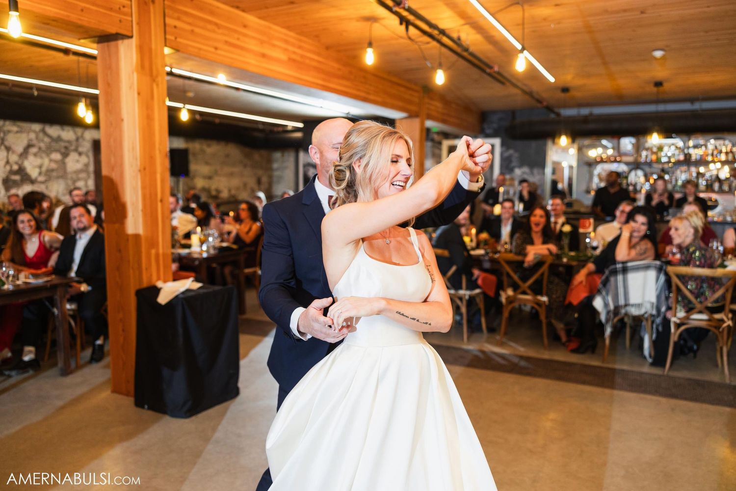 Couple performs romantic first dance at industrial-style wedding reception venue.