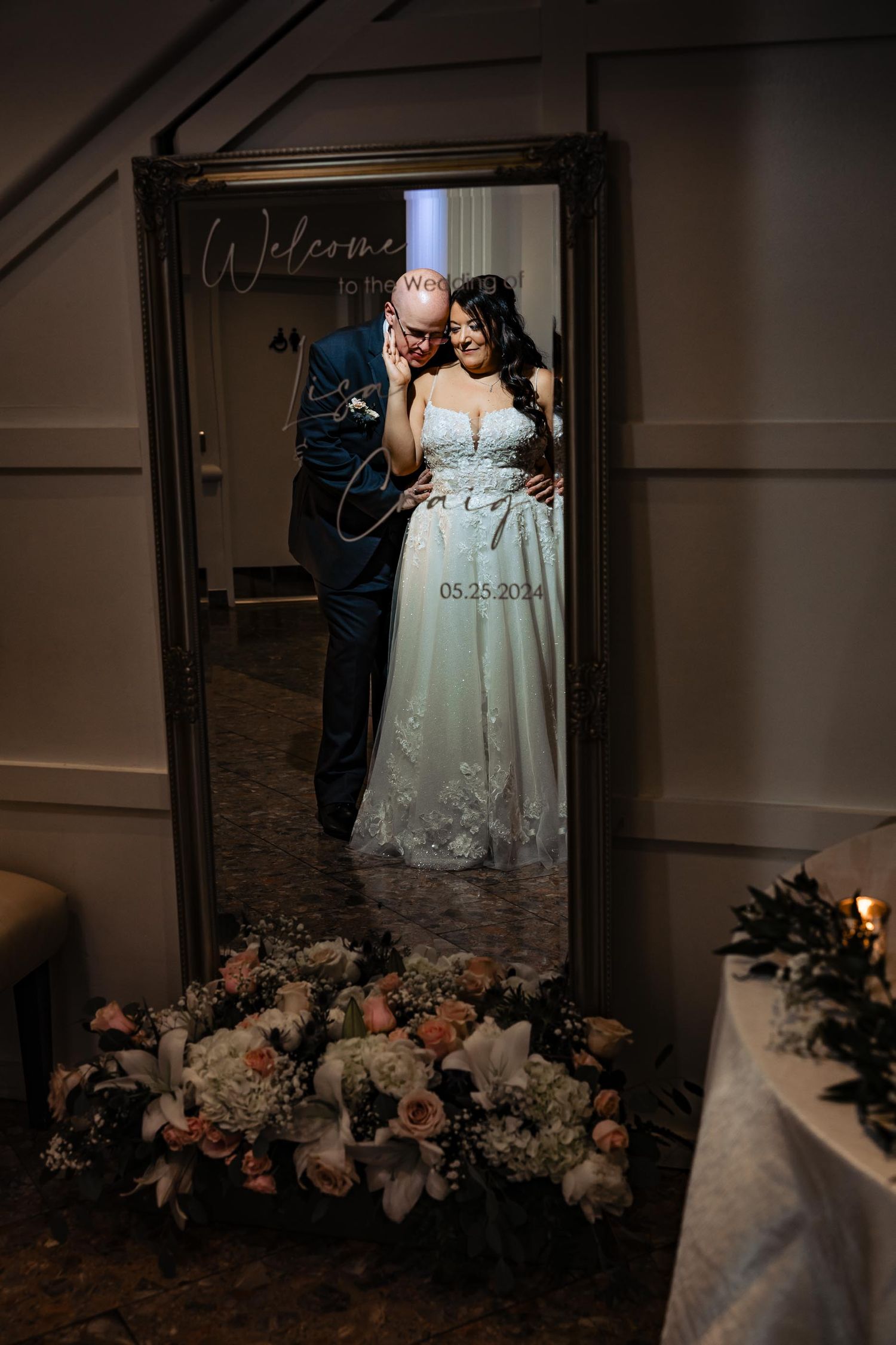 Mirror reflection of couple with floral decorations and welcome sign.