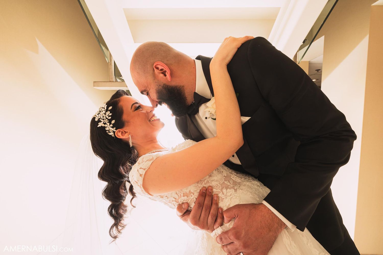 Romantic wedding dip kiss moment captured in hallway setting.