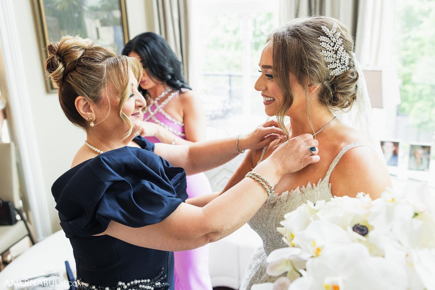Final touches being made to the bride's wedding day attire in an elegant indoor setting.